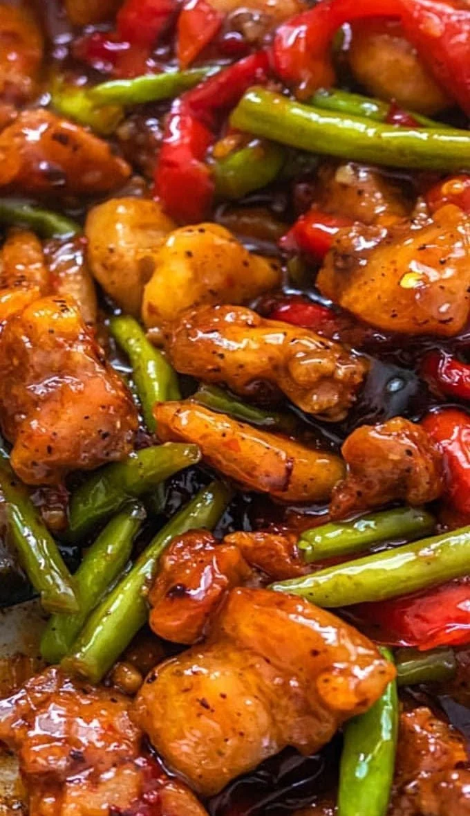 Chicken and green bean stir fry in a skillet, garnished with sesame seeds.