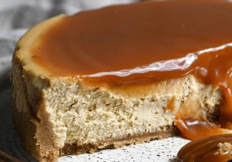 Delicious Apple Cider Cheesecake topped with caramel and apple slices.