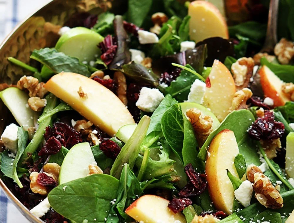 A colorful Apple Cranberry Walnut Salad with fresh fruits and nuts in a bowl.