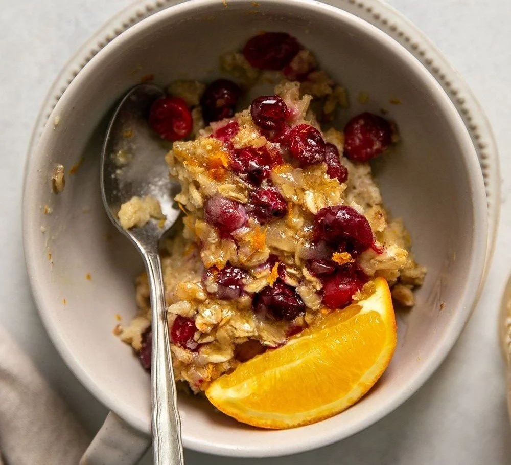 Cranberry orange baked oatmeal served in a bowl with fresh cranberries and oranges