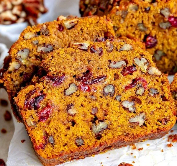 Cranberry pecan pumpkin bread fresh out of the oven, topped with nuts.