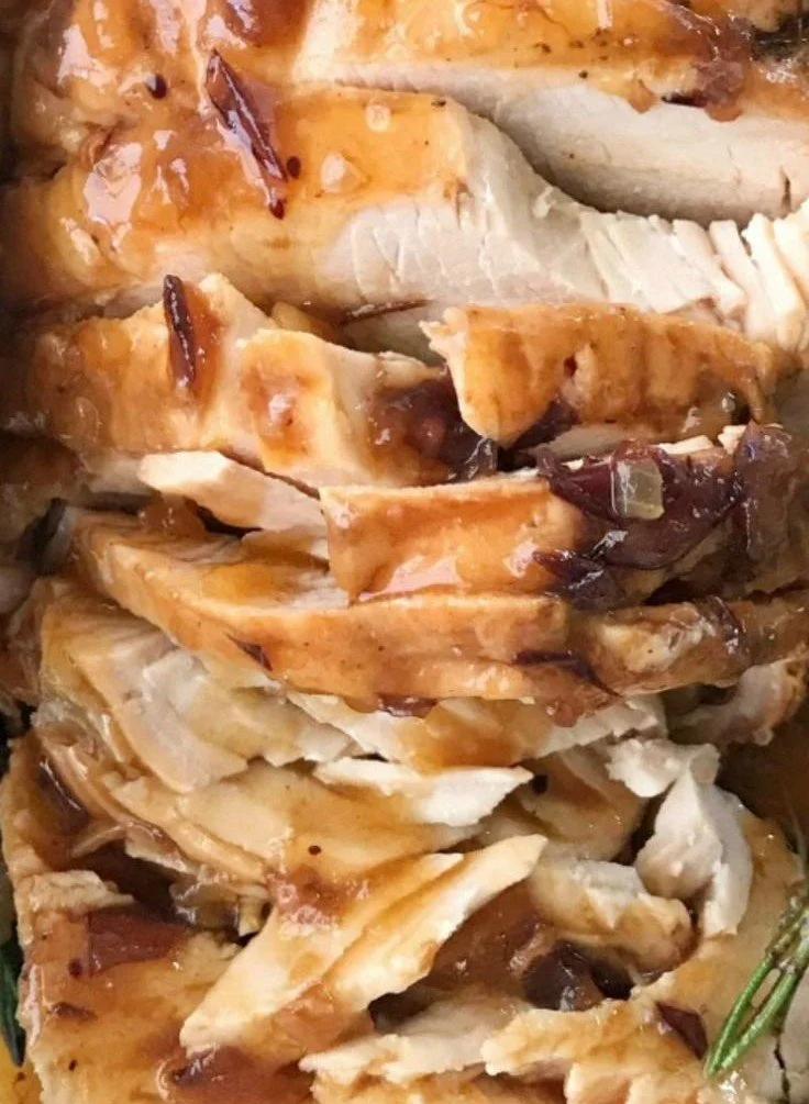 Crockpot turkey breast served with cranberry gravy on a festive table.