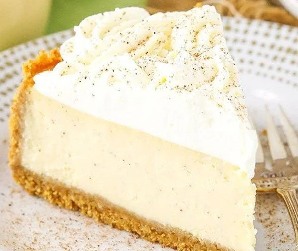 Delicious Eggnog Cheesecake topped with whipped cream and festive sprinkles.