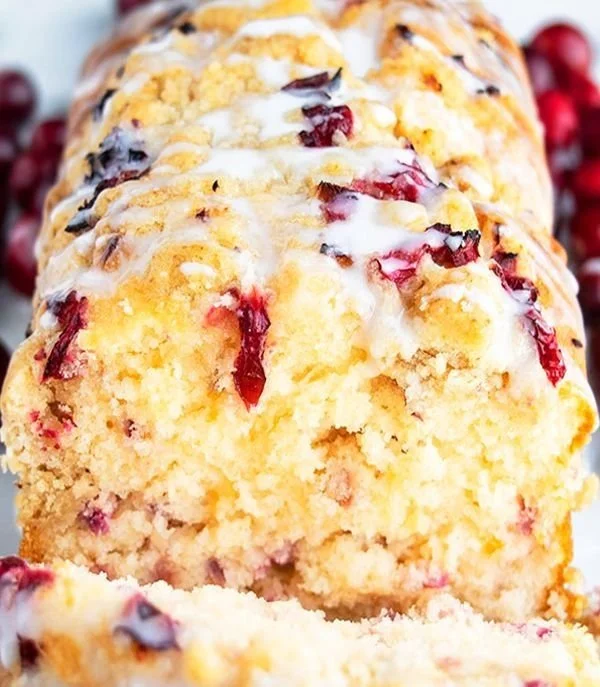 Sliced Orange-Glazed Cranberry Bread on a wooden cutting board.