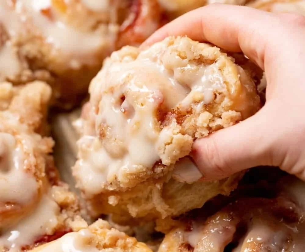 Peach cobbler cinnamon rolls with crumb streusel on a rustic dish