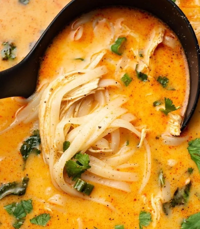 Delicious Thai Chicken Soup served in a bowl with fresh herbs and ingredients